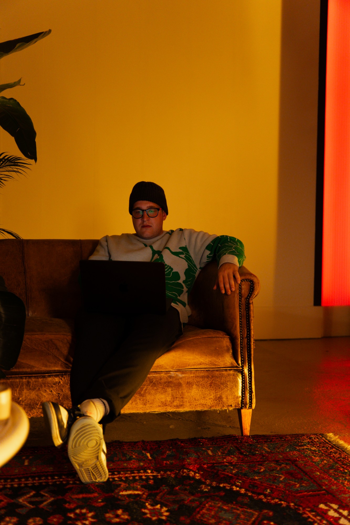 Naulé on a leather sofa with a laptop