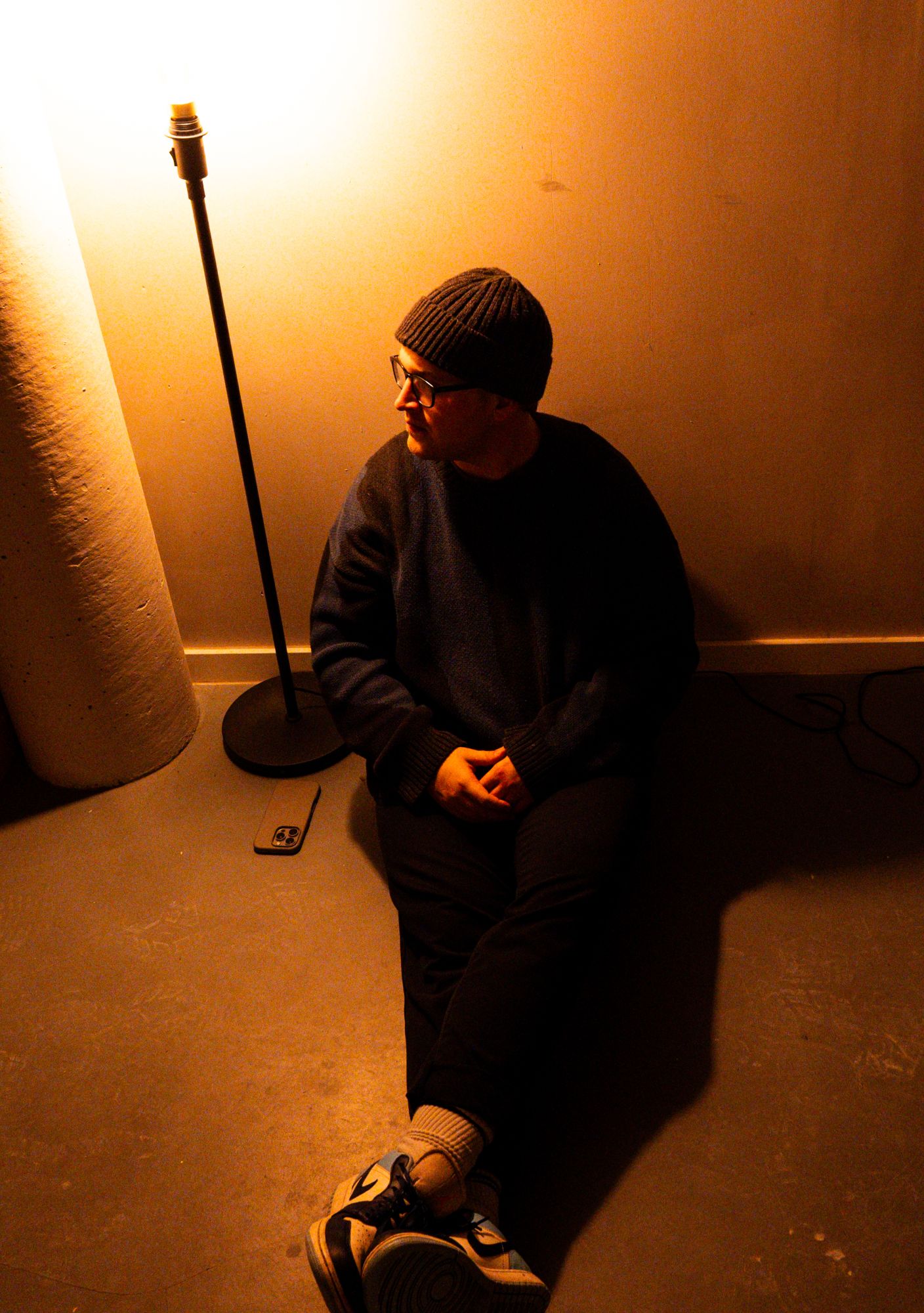 Naulé sitting on the floor beside a glowing lamp