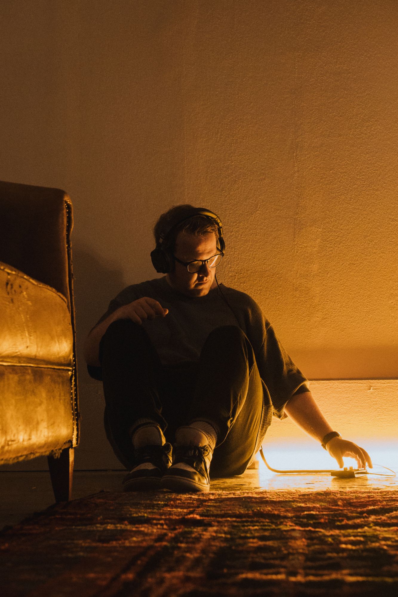 Naulé in headphones, sitting on the floor