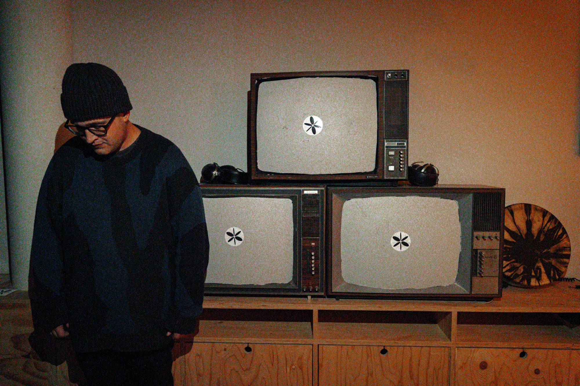 Naulé standing beside a stack of vintage televisions